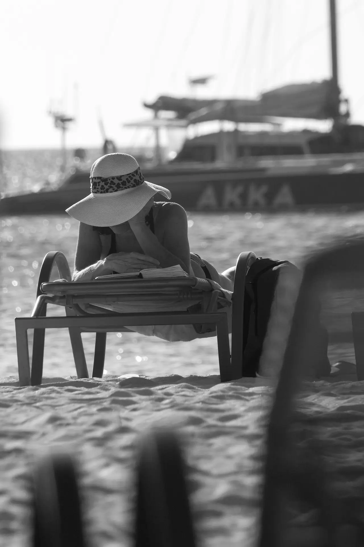 Black and white photo of a person relaxing on the beach in Oranjestad, Aruba, with a boat in the background.