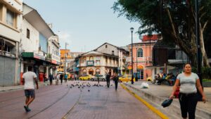 Busy urban street with people, pigeons, and taxis, showcasing colorful architecture.